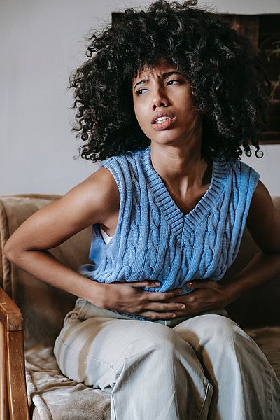 Woman in blue sweater with stomach cramps